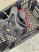 Underside view showing rails and twin springs of one saddle inside crate with second saddle visible