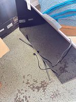 Back of TV with detached stand legs and power cord on floor