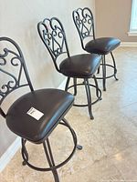 Three black metal bar stools lined up showing overall design