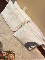 Two packaged Sleep Number pillows leaning against wall