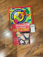 Dictionary and game box together on wood floor