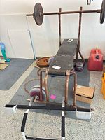 Overall view: bench with rack, barbell loaded with plates, additional plates on floor