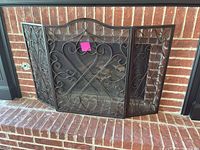 Front view of folded 3-panel fireplace screen showing scrollwork and mesh