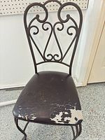 Front view of chair showing peeling seat upholstery and scroll back design