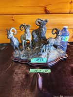 Full view of brass bighorn ram sculpture on wood base with measurement note