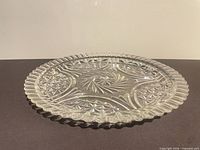 Side view of clear pressed glass platter showing scalloped rim and pressed pattern