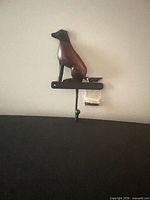 Front view of rustic dog wall hook showing wood dog figure on metal bar with hook and hardware bag