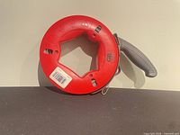 Front view of Gardner Bender red fish tape reel with gray handle