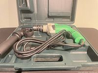 Drill, side handle, and power cord inside carrying case