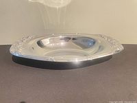 Top view of silver-plated oval serving tray showing floral embossed rim and reflective surface