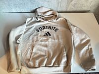 Full view of beige Fortnite Adidas hoodie laid flat showing front, pocket and sleeves