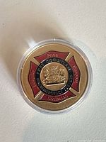 Front of gold-tone challenge coin with red enamel Maltese cross design