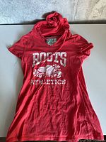 Full view of red Roots hooded T-shirt showing front graphic and overall condition