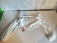 Full view of white cropped top with long sleeves and zipper