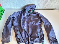 Full view of purple The North Face jacket laid flat showing hood, sleeves, hem
