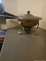 Side view showing copper body, twin handles, brass stand and burner