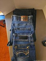 Stack of three jeans showing Lee leather patch on top pair, others beneath