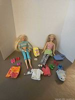 Overview of both Barbie dolls, baby doll, clothing pieces, shoes and accessories