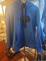 Front view of blue The North Face hoodie on hanger