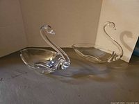 pair of clear glass swan dishes side by side