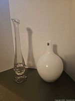 Tall clear glass vase and white round vase side by side