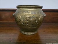 Front view of cast brass jardiniere showing gourd and vine relief and geometric rim