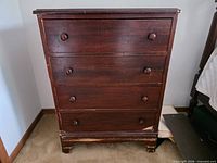 Front view of dark brown 4-drawer dresser showing overall design and knobs