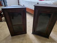Two mahogany wall cabinets standing upright, front glass doors visible