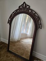 Full view of arched wood mirror leaning against wall