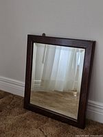 Full view of mirror leaning against wall on carpet
