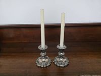 Full view of the pair of silver-plated candlesticks with taper candles inserted