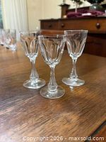 Three matching clear pressed cordial glasses on wooden table