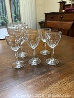 Group of five matching crystal wine glasses on wooden table