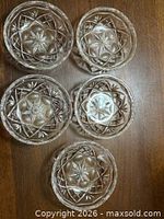 Top view of five matching clear glass bowls showing Star of David motif and scalloped rims on wooden surface