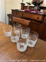 Six Baccarat Harmonie crystal tumblers on wooden surface displaying vertical cuts and monogram