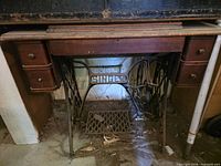 Full front view of Singer treadle sewing machine cabinet with cast iron base and drawers