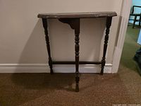 Front view of dark brown console table showing turned legs and stretcher
