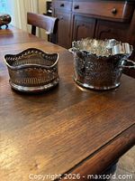 Both silver-plated coasters on table showing designs and condition