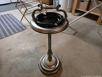 Full view of cast metal pedestal ashtray stand showing handle, black glass tray, marble base