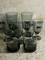 Eight smoked green glasses arranged upright showing sizes