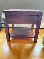 Front view of solid wood end table showing drawer and lower shelf