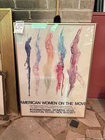 Full view of framed poster showing abstract figures and event text
