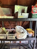 Overall view showing metal toolbox, plastic organizers, bins, steel wool box, sponges and rags on shelving