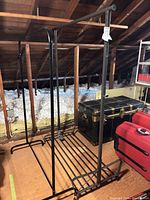 Both black metal garment racks in attic space