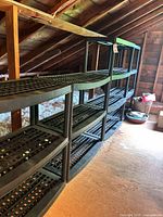 Row of four black plastic shelving units in attic