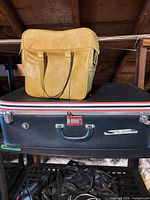 Black suitcase with yellow tote resting on top