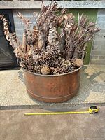 front view of copper tub filled with dried botanicals with tape measure for scale