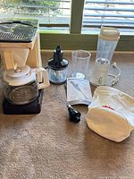 Full lot showing coffeemaker, immersion blender motor, chopper bowl, blending cup, travel bottle, manual, storage bag