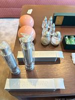 Overview showing two pepper pumps in boxes, two pink ceramic shakers, four faceted crystal shakers, cocktail picks in green box, two loose picks
