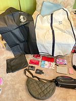 Overall view with garment bags, small wallets and pouches, quilted crossbody, black zip bag